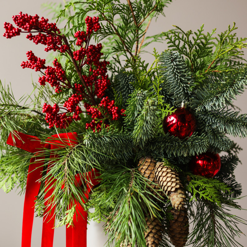 Новогодний букет из живой хвои с шишками, красными ягодами и бантами в кашпо