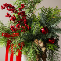 Новогодний букет из живой хвои с шишками, красными ягодами и бантами в кашпо