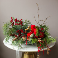 Композиция из живой хвои с красными свечами и золотой лошадкой-качалкой