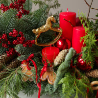 Композиция из живой хвои с красными свечами и золотой лошадкой-качалкой