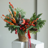 Композиция из живой хвои с оранжевым декором и снегирем