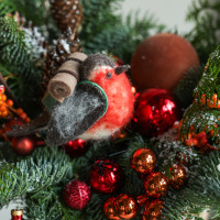 Композиция из живой хвои с оранжевым декором и снегирем