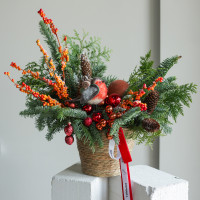 Композиция из живой хвои с оранжевым декором и снегирем