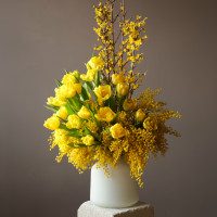 Букет с мимозой и желтыми тюльпанами в дизайнерской вазе
