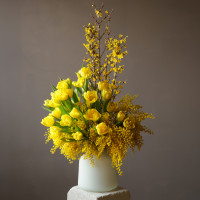 Букет с мимозой и желтыми тюльпанами в дизайнерской вазе