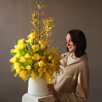 Букет с мимозой и желтыми тюльпанами в дизайнерской вазе