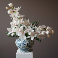 Белые орхидеи в дизайнерской вазе с эвкалиптом