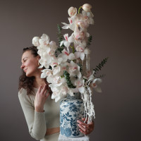 Белые орхидеи в дизайнерской вазе с эвкалиптом и стабилизированным амарантом