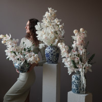 Белые орхидеи в дизайнерской вазе с эвкалиптом и стабилизированным амарантом