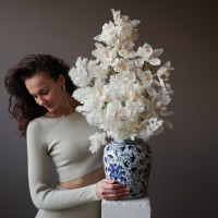 Белые орхидеи в дизайнерской вазе со стабилизированным аспарагусом