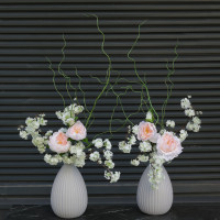 Композиция с пионовидными розами и цветущими ветками вишни в дизайнерской вазе