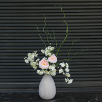 Композиция с пионовидными розами и цветущими ветками вишни в дизайнерской вазе