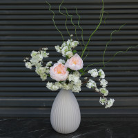 Композиция с пионовидными розами и цветущими ветками вишни в дизайнерской вазе