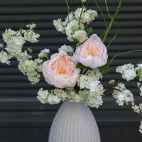 Композиция с пионовидными розами и цветущими ветками вишни в дизайнерской вазе