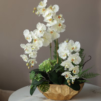 Композиция с белыми орхидеями и декоративной зеленью в дизайнерской золотой вазе 