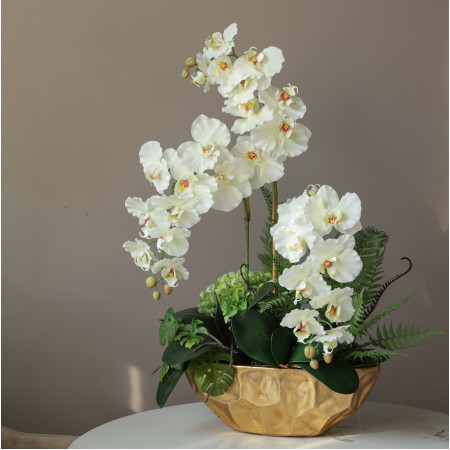 Композиция с белыми орхидеями и декоративной зеленью в дизайнерской золотой вазе 