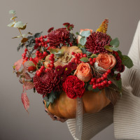 Осенняя композиция в настоящей тыкве с винными хризантемами и ягодами